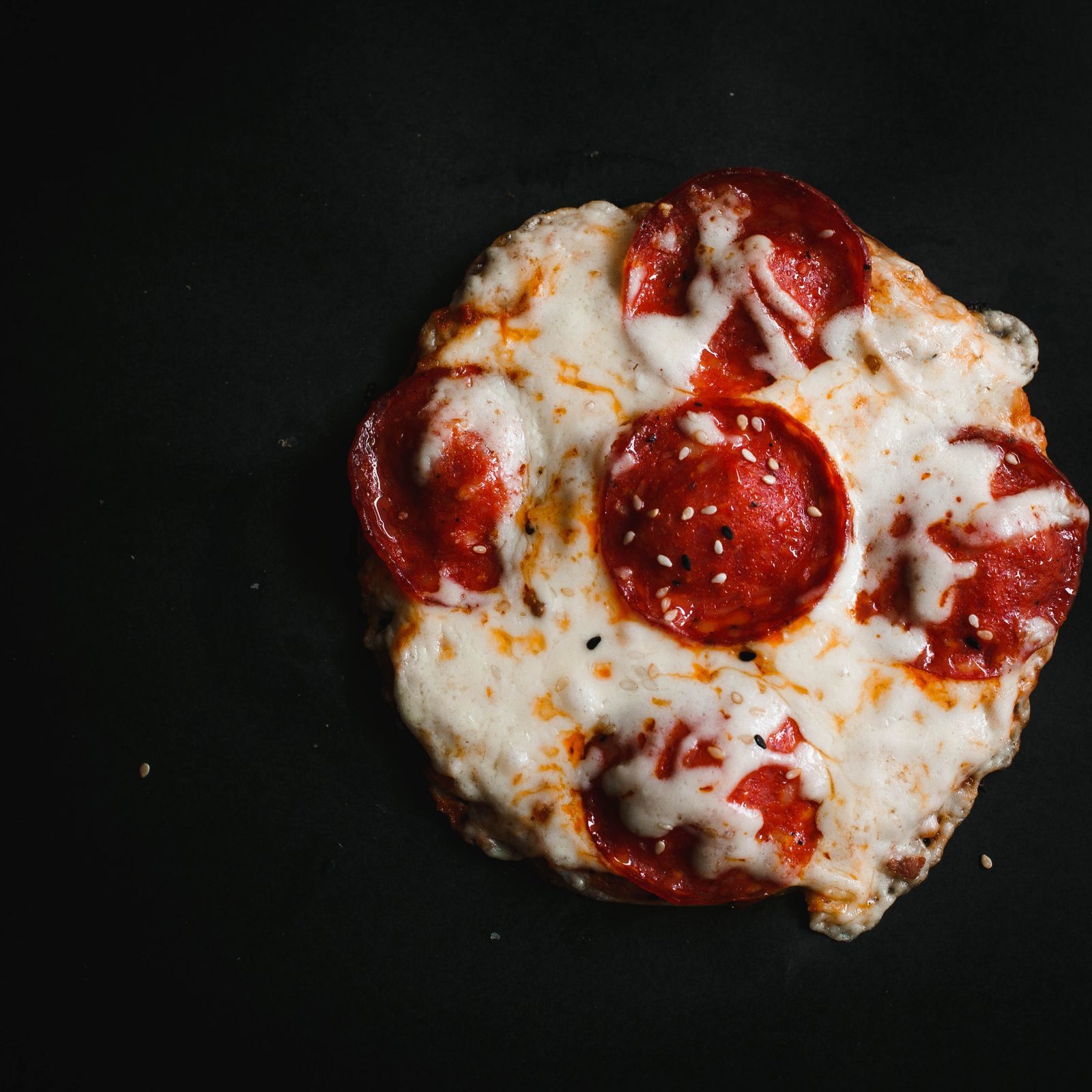 A whole pepperoni pie on a black surface