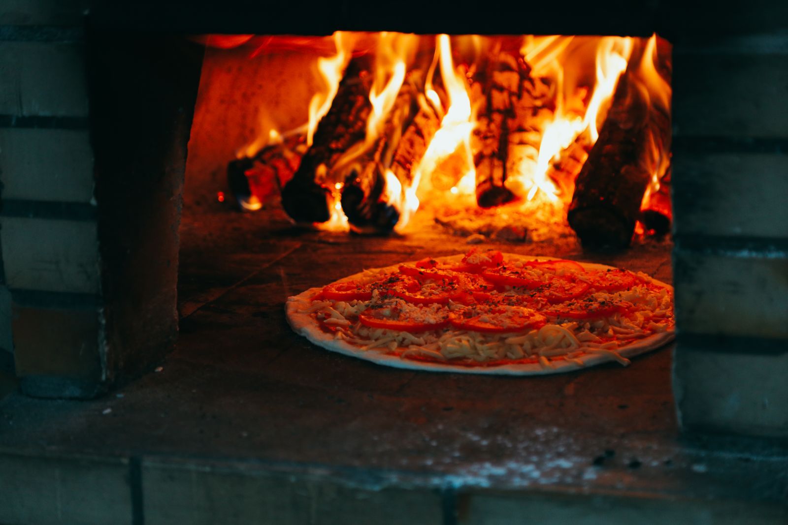 A pie going into the wood-fired oven on a peel