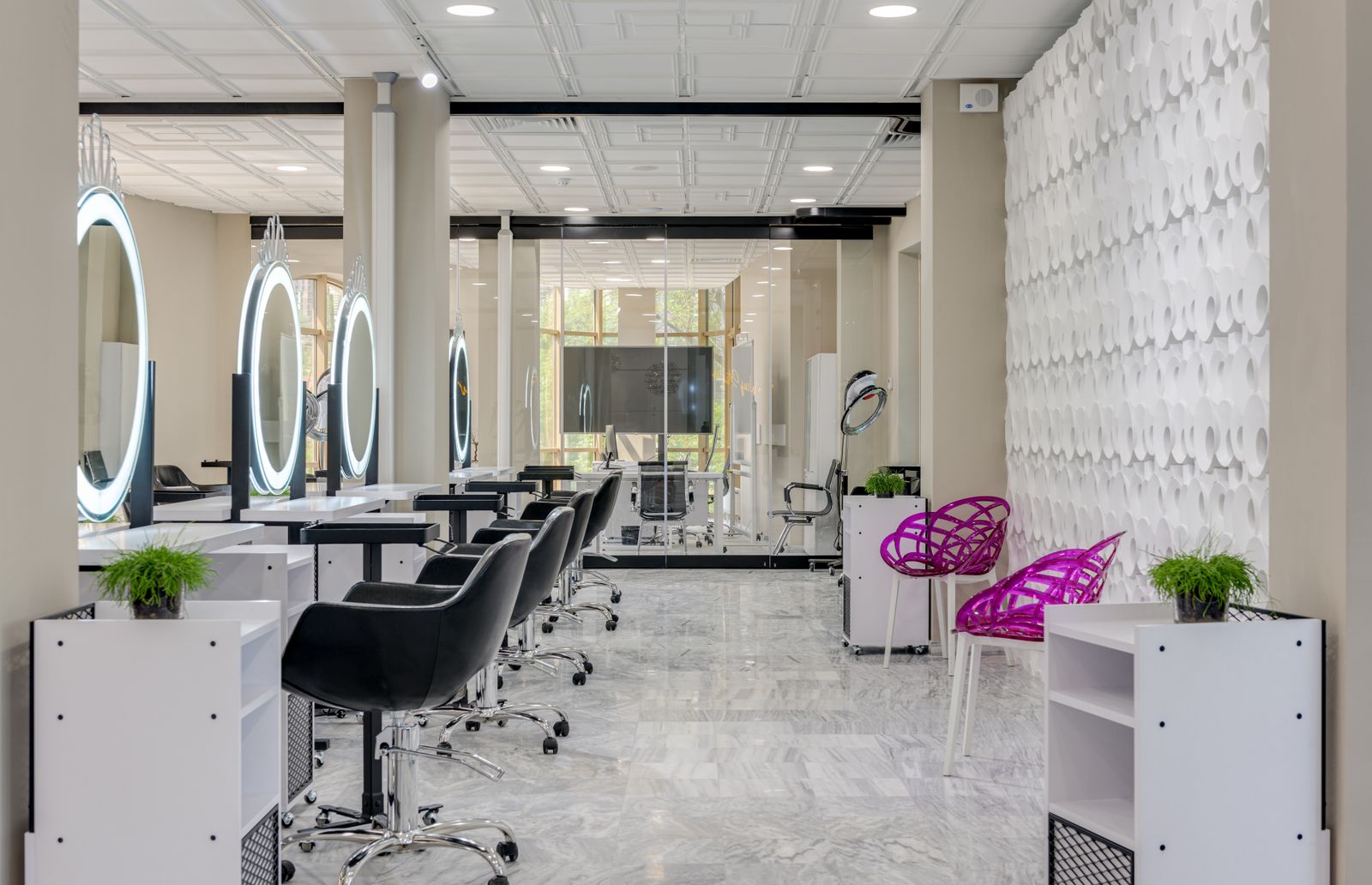 The salon floor: white walls, black chairs, round lit mirrors and marble floors